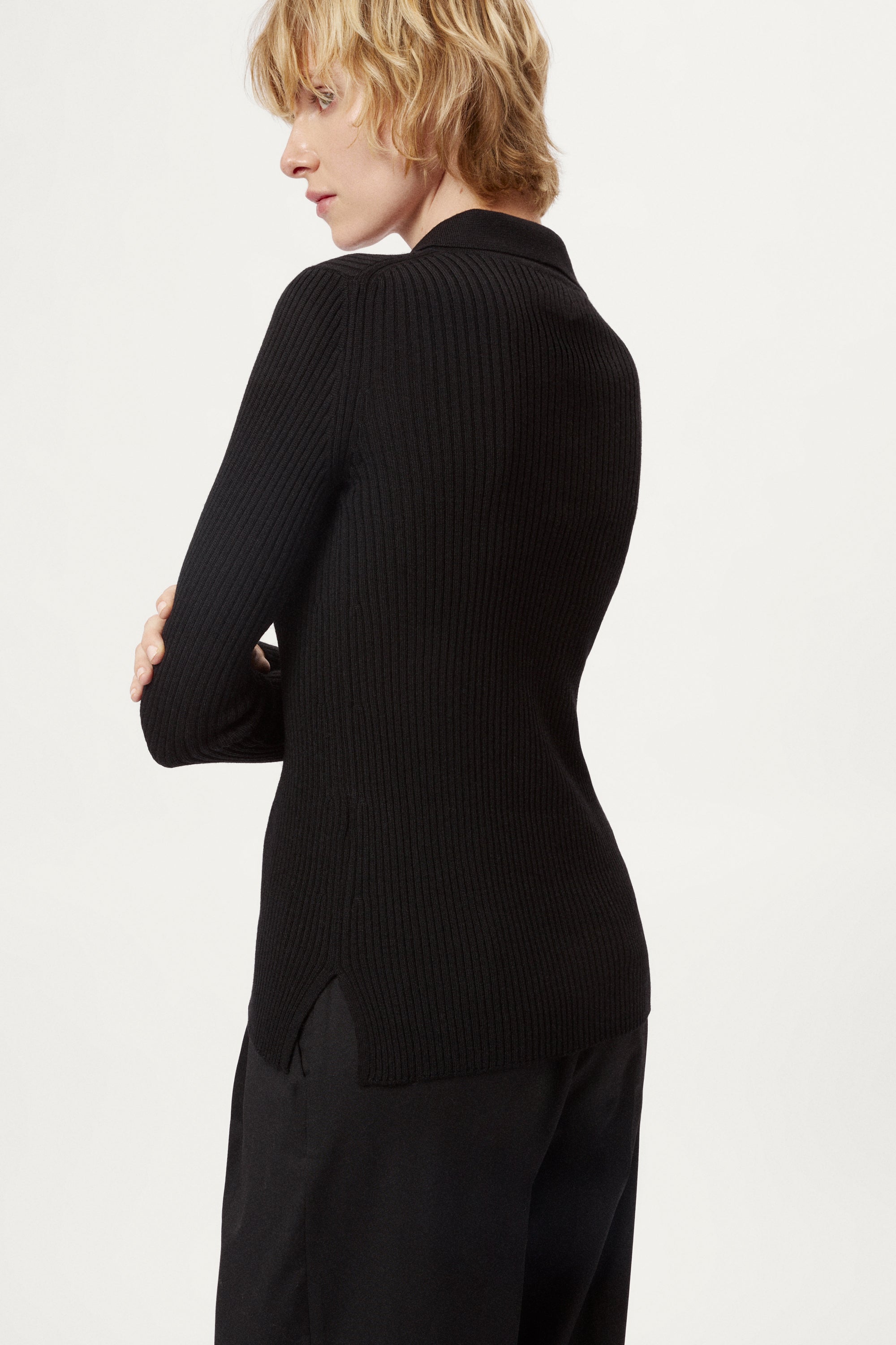 Woman wearing a black ribbed merino shirt on a white background