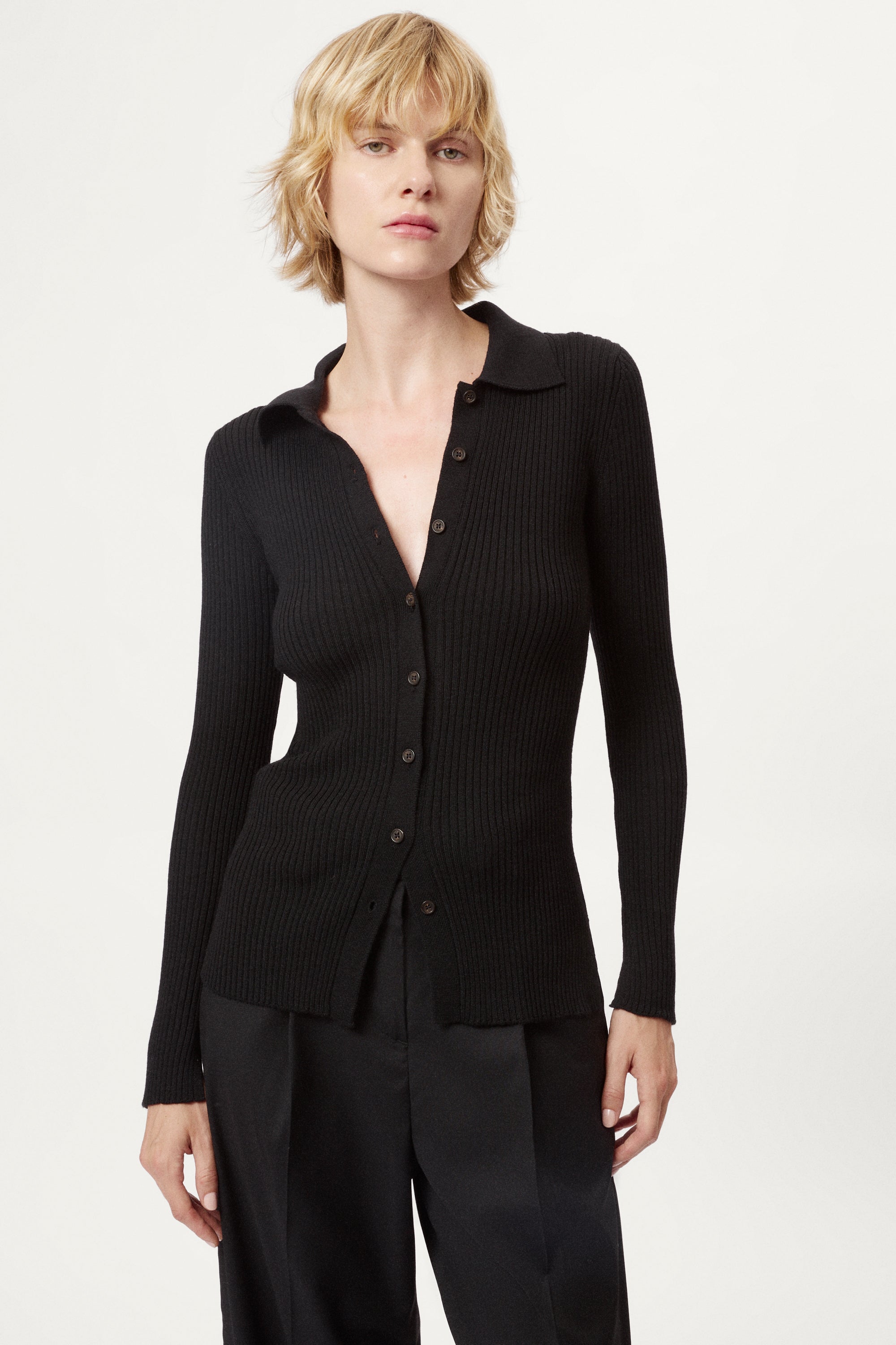 Woman wearing a black ribbed merino shirt  on a white background