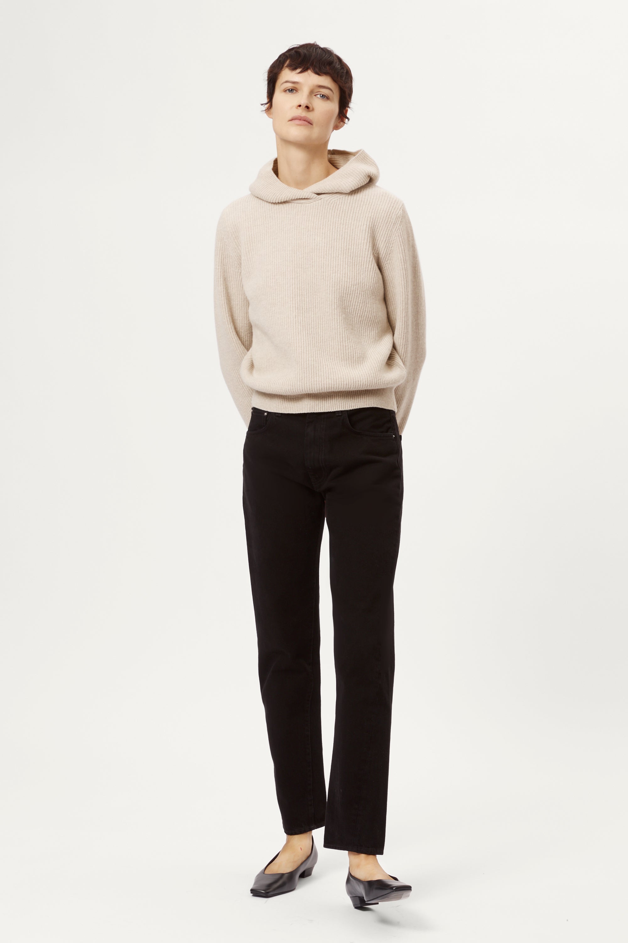 Person wearing a woolen ecru hoodie sweater on a white background
