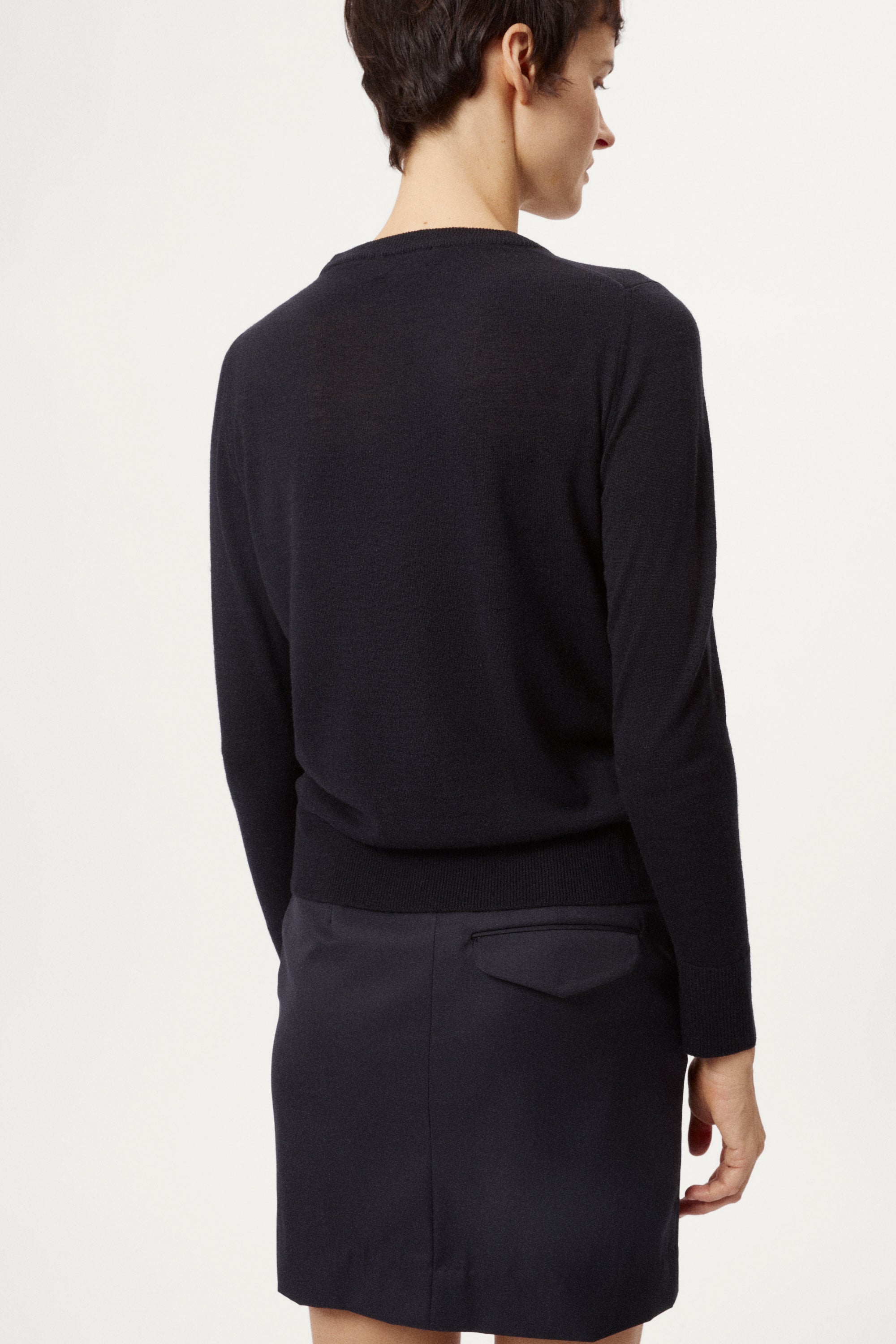 Person wearing a blackwool long-sleeve sweater and skirt 